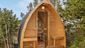 Une cabane en bois avec un toit en pente, un banc et une porte.