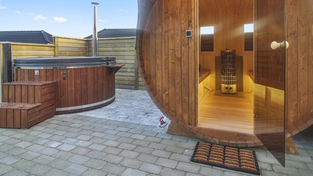 En träbeklädd bastu med en välvd ingång, ett bubbelbad och en metallkamin.