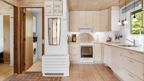 Une cuisine moderne équipée d’un four encastré, d’un lave-linge et d’un grand miroir.