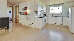 Une cuisine moderne avec des meubles blancs, un plancher en bois et une fenêtre qui laisse entrer la lumière naturelle.