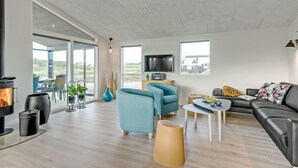 Uma sala de estar moderna com lareira, assentos confortáveis e janelas amplas com vista para o exterior.
