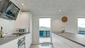 Cozinha moderna com micro-ondas embutido, taça de vinho e garrafa sobre o balcão.