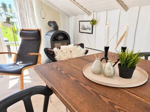Een houten tafel met een zacht, wit kussen, twee glazen vazen en een plant in pot op een beige dienblad.