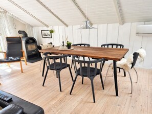 Een eetgedeelte met een houten tafel, zwarte stoelen, een open haard en een bank.