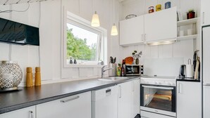 Une cuisine moderne avec des meubles blancs, un plan de travail noir, une fenêtre et un four de la marque Voss.