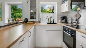 Eine moderne Küche mit weißen Schränken, einer Holz Arbeitsplatte, einem eingebauten Backofen und Pendelleuchten.