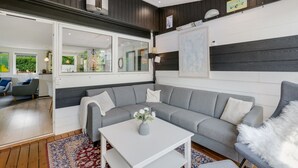 Ein modernes Wohnzimmer mit grauem Sofa, weißem Couchtisch und einem gemusterten Teppich.