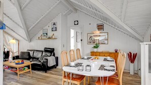 A cozy loft-style room with a high ceiling, a dining table with chairs, a sofa, and a bookshelf. - "Anu" - 300m to the fjord by Interhome (Hemmet)