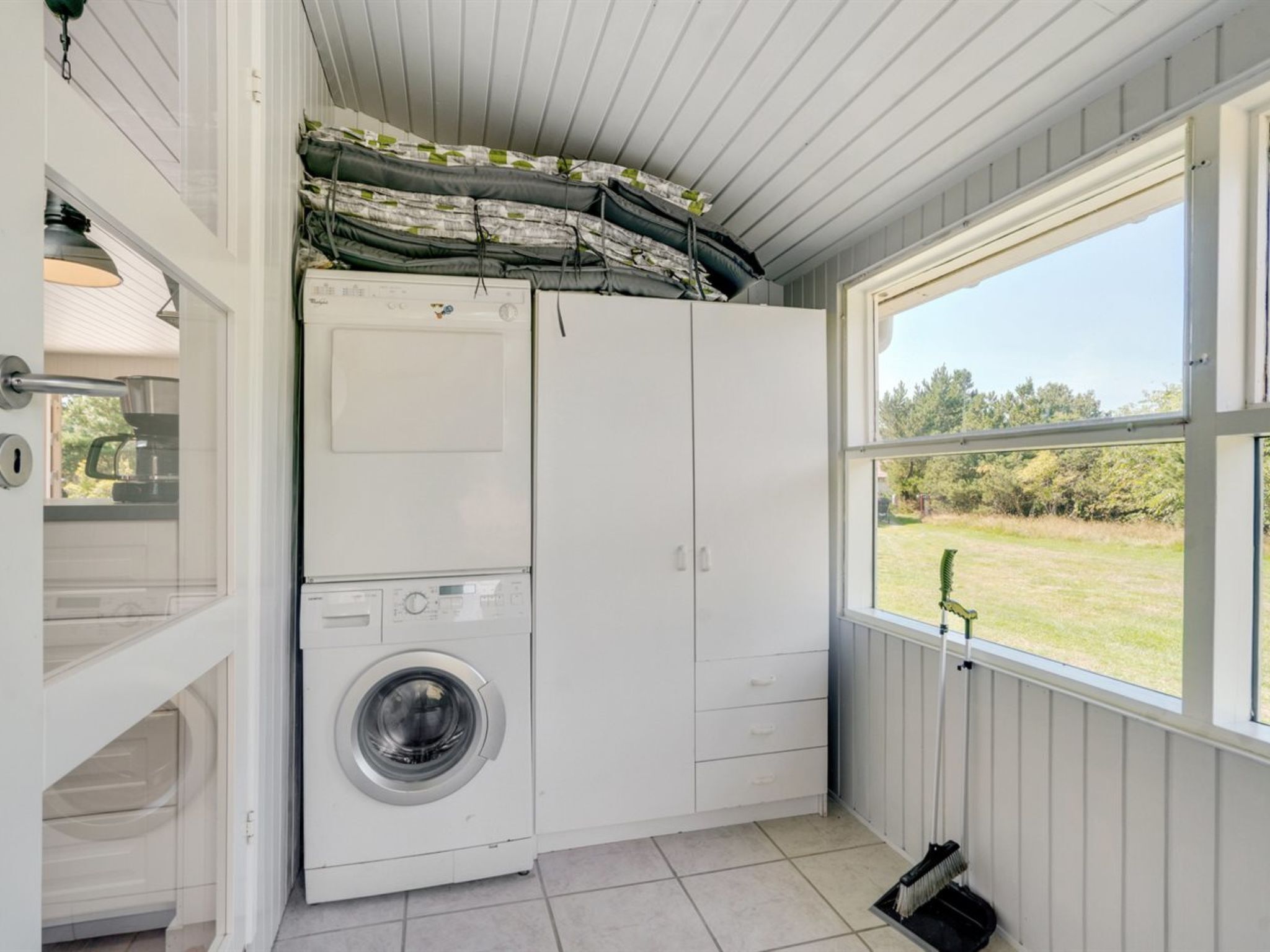 A compact laundry room with a washing machine, a dryer, and a window providing a view of the outdoors.