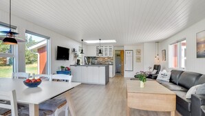 A modern kitchen with white cabinets, a central island, and a dining area with a table and chairs. - "Thorvor" - 1.5km from the sea by Interhome (Blåvand)
