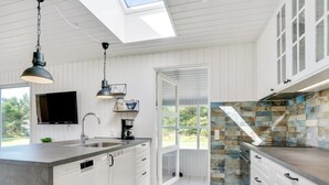 A modern kitchen with white cabinetry, a large island, a built-in oven, and a stone backsplash. - "Thorvor" - 1.5km from the sea by Interhome (Blåvand)