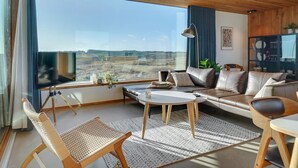 A modern living room with a large window, a sofa, a coffee table, and a chair. - "Caterina" - 100m from the sea by Interhome (Blåvand)