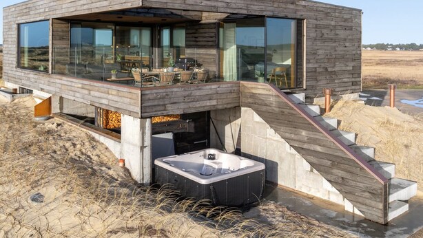 A modern house with a wooden exterior, large windows, a hot tub, and a staircase leading to a deck. - "Caterina" - 100m from the sea by Interhome (Blåvand)