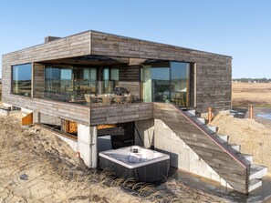A modern house with a wooden exterior, large windows, a hot tub, and a staircase leading to a deck. - "Caterina" - 100m from the sea by Interhome (Blåvand)
