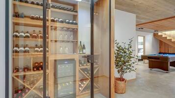 A modern interior with a wine cellar, a pool table, and a staircase.
