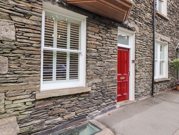 A stone building with a red door and white-framed windows. - 1a Biskey Howe (Windermere)