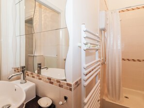 A bathroom with a sink, mirror, and a shower with a towel rack. - 1a Biskey Howe (Windermere)