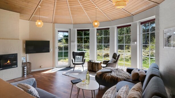 A modern living room with a fireplace, large windows, and a ceiling with wooden beams. - "Ingmund" - 2km from the sea by Interhome (Blåvand)