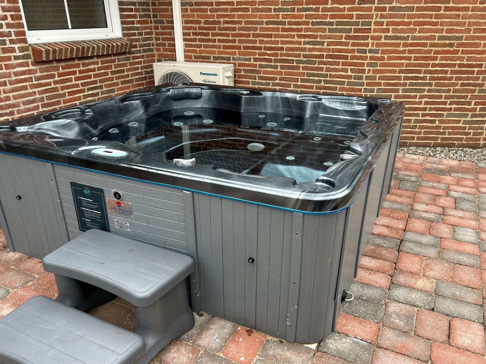 A hot tub with a glass top, a step for access, and a label indicating it is a DenFam product.