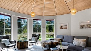 A modern living room with a large window, a sofa, a chair, and a small table. - "Ingmund" - 2km from the sea by Interhome (Blåvand)