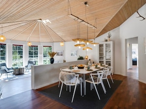 A spacious dining area with a high wooden ceiling, a central island with seating, and pendant lighting.