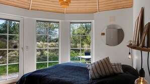 A bedroom with a large bed, a round mirror, and a view of the outdoors. - "Ingmund" - 2km from the sea by Interhome (Blåvand)