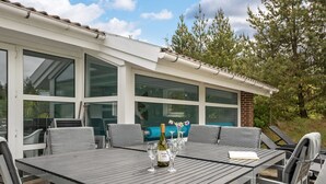 An outdoor patio with a table set for dining, surrounded by chairs. - "Rudy" - 900m to the fjord by Interhome (Blåvand)
