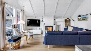 A modern living room with a blue sofa, a TV mounted on the wall, and a fireplace. - "Egbert" - 900m from the sea by Interhome (Vejers Strand)