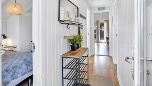 A hallway with a bed, a hanging lamp, a mirror, a small table with a plant, and a door leading to another room. - "Egbert" - 900m from the sea by Interhome (Vejers Strand)