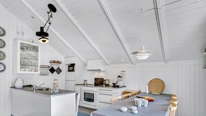 A modern kitchen with white cabinetry, a central island, and a dining area with a long table and chairs. - "Egbert" - 900m from the sea by Interhome (Vejers Strand)