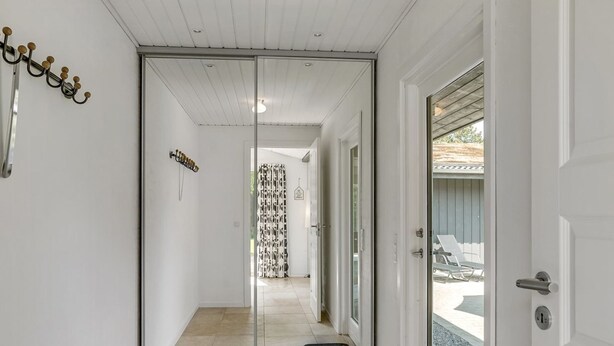 A hallway with a sliding glass door leading to an outdoor area with a pool and lounge chairs.