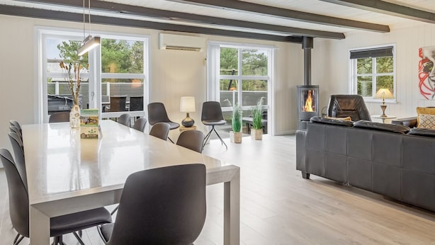 A modern living room with a fireplace, a dining area with chairs, and large windows. - "Madalena" - 2.8km from the sea by Interhome (Rømø)