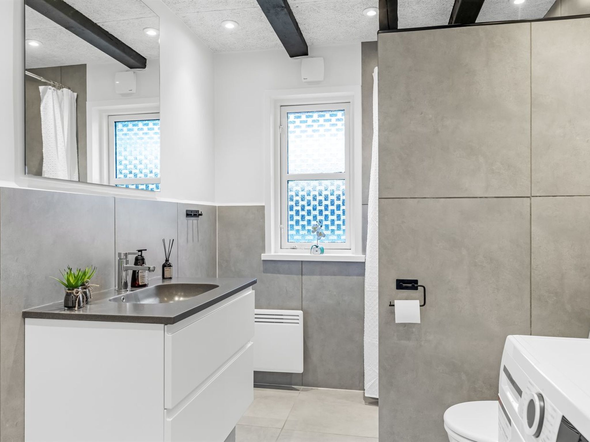 A modern bathroom with a sink, mirror, and toilet.
