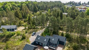 Une maison moderne dotée d’une terrasse, entourée d’une forêt dense et offrant une vue sur un lac.
