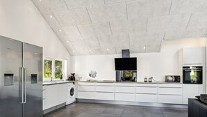 Une cuisine moderne équipée d’un lave-linge intégré, d’un grand réfrigérateur et d’un four à micro-ondes.