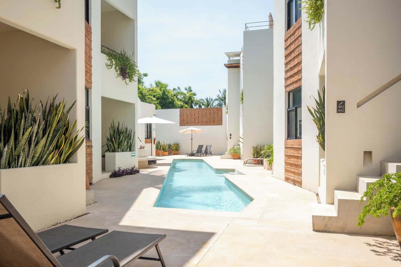 A modern outdoor pool area with a rectangular pool, lounge chairs, and potted plants.