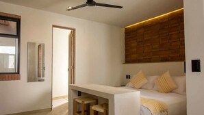 A modern bedroom with a bed, a desk, and two stools.