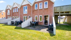 A row of brick houses with white trim, a covered outdoor seating area, and a wooden deck.