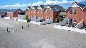 A row of red brick houses with white trim, each with a small front yard and a gravel driveway.
