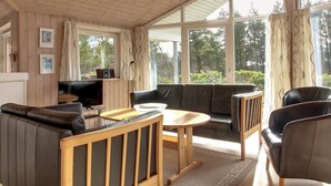 A modern living room with a sofa, chairs, a TV, and a dining table.