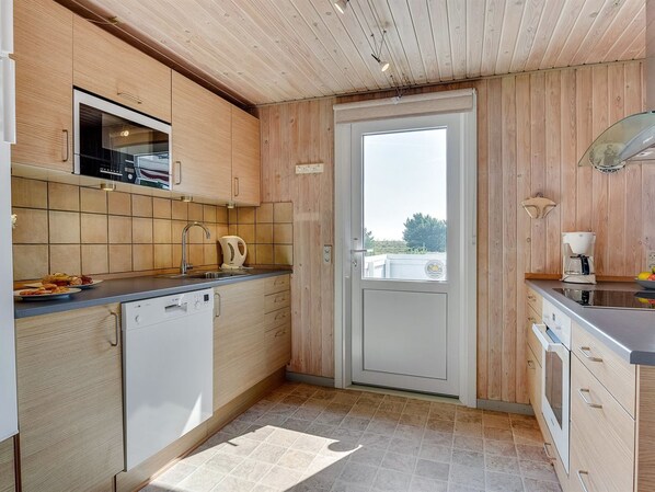 A compact kitchen with wooden cabinets, a built-in microwave, a coffee maker, and a view through the door. - "Gabriela" - 1km from the sea by Interhome (Rømø)