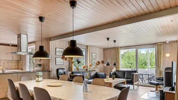 Een moderne keuken met een centraal eiland, een eethoek met een ronde tafel, en een gezellige zithoek met een bank en stoelen.