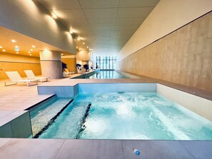 Swim laps or relax by the pool in a spacious, well-lit area with lounge chairs and a seating area.