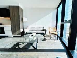 Relax in a stylish living space with a tufted sofa, wooden chair, and floor lamp.