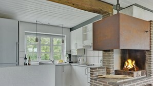 A modern kitchen with a brick fireplace, white cabinetry, and a large window. - "Thorben" - 3.5km from the sea by Interhome (Rømø)