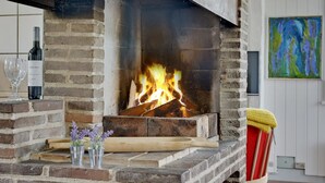 A brick fireplace with a fire burning, a wine bottle, and glasses on the mantel. - "Thorben" - 3.5km from the sea by Interhome (Rømø)