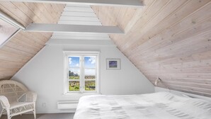A bedroom with a sloped ceiling, a large window, a bed, and a wicker chair. - "Thorben" - 3.5km from the sea by Interhome (Rømø)