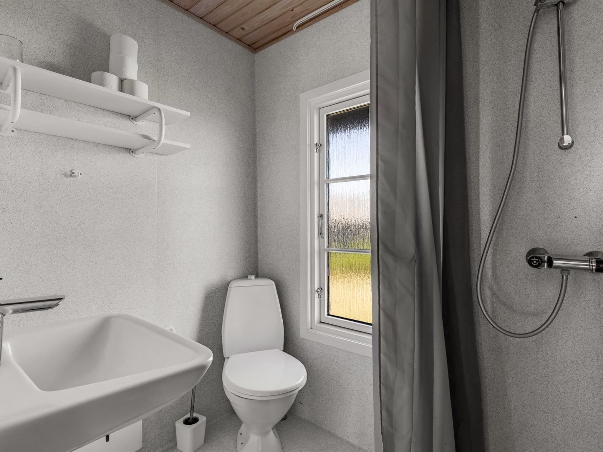 Ein Badezimmer mit Toilette, Waschbecken, Dusche und einem Fenster mit Blick.