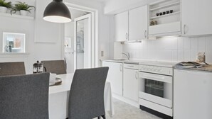 A modern kitchen with white cabinetry, a built-in oven, and a dining area with a table and chairs. - "Withulf" - 2.3km from the sea by Interhome (Rømø)