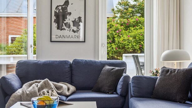 A modern living room with a blue sofa, a glass bowl with fruits, and a framed map of Denmark on the wall. - "Withulf" - 2.3km from the sea by Interhome (Rømø)